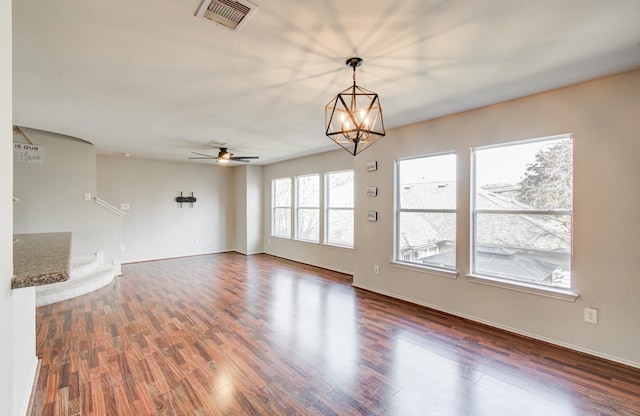 empty room featuring ceiling fan with notable chandelier and dark hardwood / wood-style floors