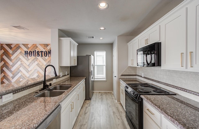 kitchen featuring sink, black appliances, white cabinets, and light stone countertops