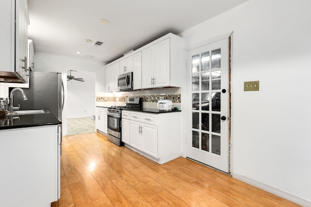 kitchen featuring appliances with stainless steel finishes, white cabinetry, backsplash, and sink