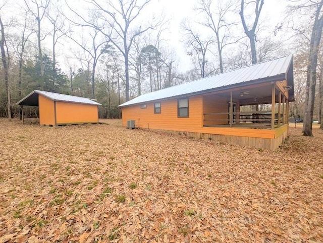 view of side of home with metal roof, central AC unit, and an outdoor structure