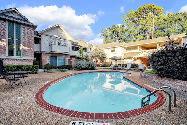 community pool with a patio area and fence