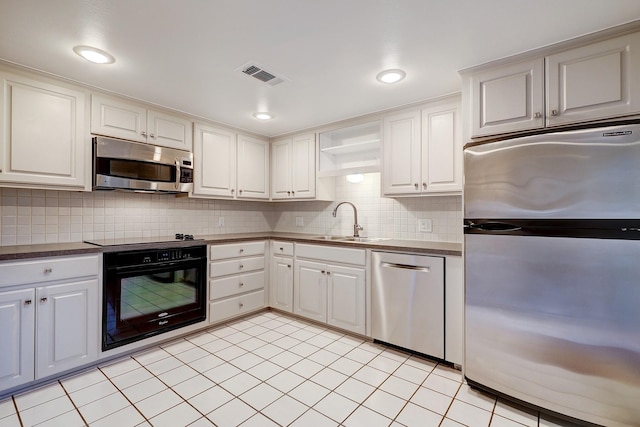 kitchen with a sink, visible vents, white cabinetry, black appliances, and dark countertops