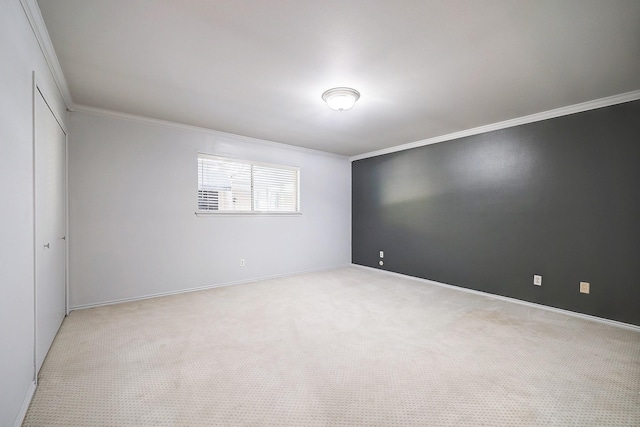 spare room featuring light colored carpet, crown molding, and baseboards