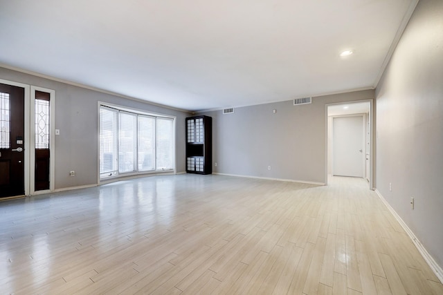 unfurnished living room featuring light wood-style floors, visible vents, ornamental molding, and baseboards