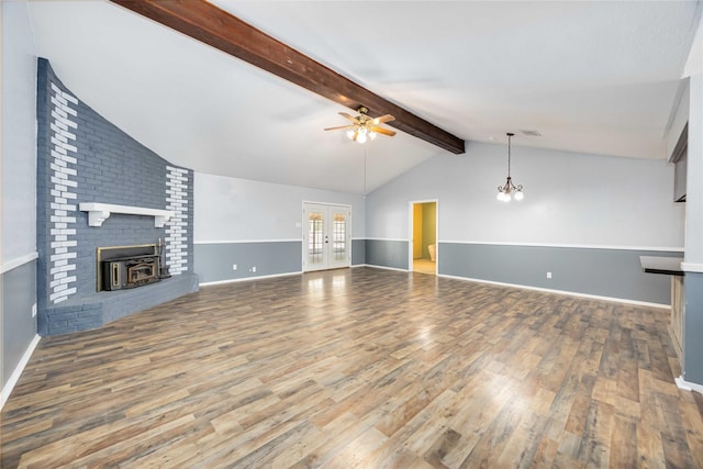 unfurnished living room with lofted ceiling with beams, ceiling fan with notable chandelier, wood finished floors, visible vents, and baseboards