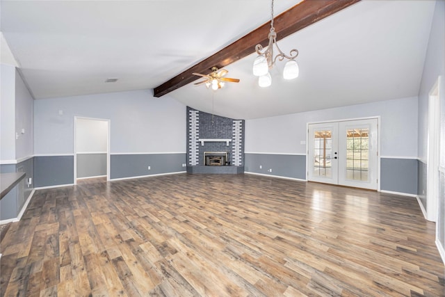 unfurnished living room with vaulted ceiling with beams, wood finished floors, a ceiling fan, french doors, and a brick fireplace