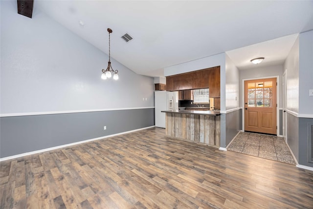 kitchen featuring a peninsula, wood finished floors, visible vents, open floor plan, and decorative light fixtures