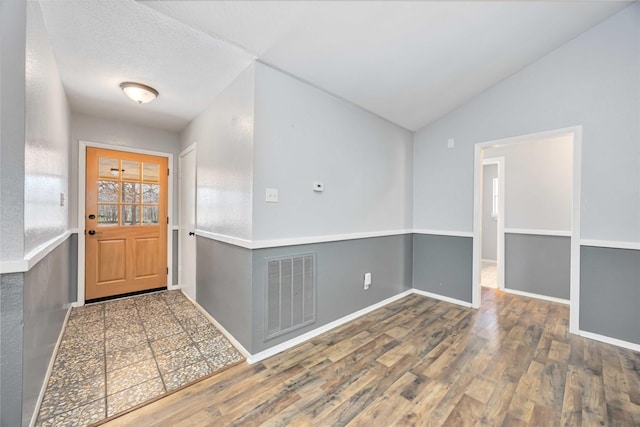 entryway featuring a textured ceiling, visible vents, baseboards, vaulted ceiling, and dark wood-style floors