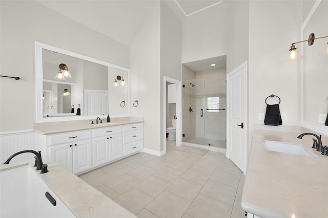 bathroom featuring toilet, a high ceiling, vanity, tile patterned floors, and a stall shower