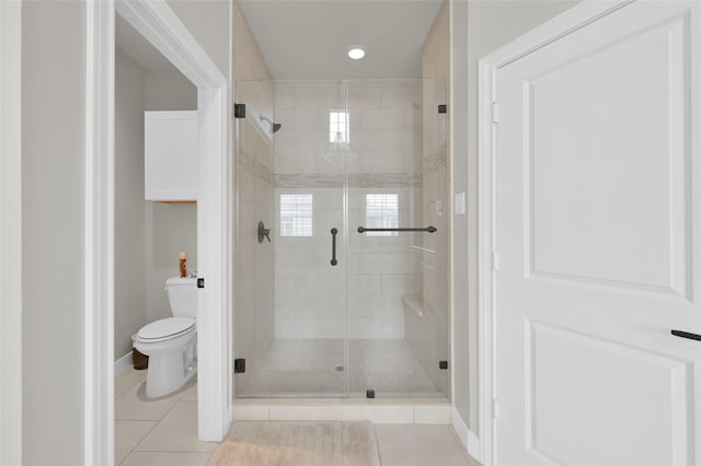 bathroom featuring a stall shower, toilet, and tile patterned floors