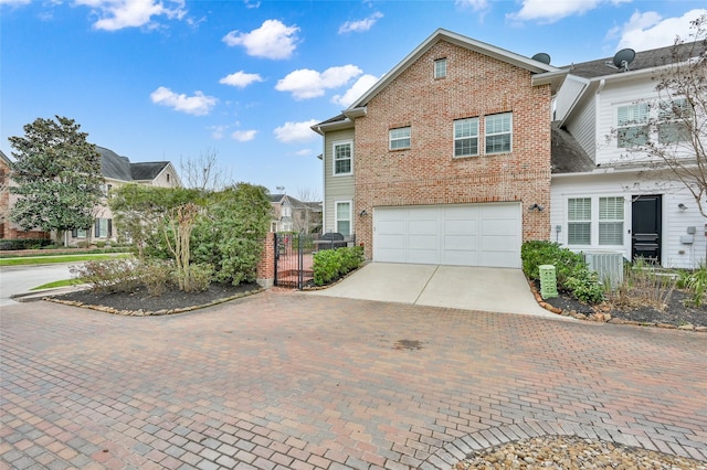 traditional home featuring a garage, decorative driveway, brick siding, and fence