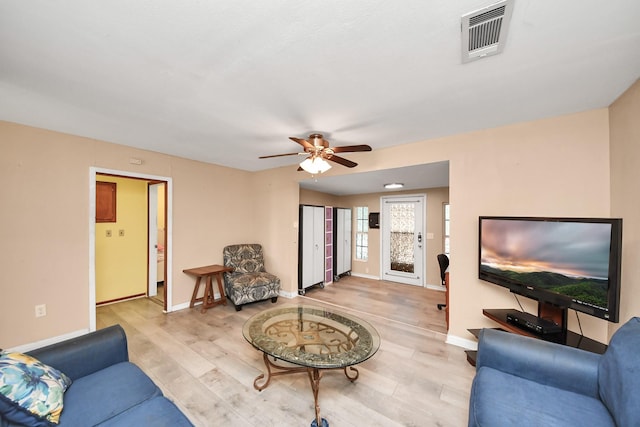 living area with a ceiling fan, light wood-style floors, visible vents, and baseboards