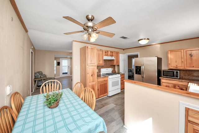 kitchen featuring under cabinet range hood, visible vents, light brown cabinets, and stainless steel appliances