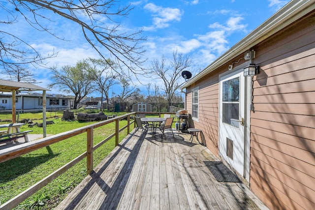 wooden terrace featuring an outbuilding, a fenced backyard, a storage shed, and a yard