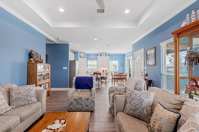 living room featuring hardwood / wood-style flooring, crown molding, and a tray ceiling