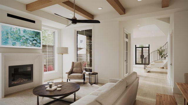 living room with beam ceiling, light hardwood / wood-style flooring, ceiling fan, and a healthy amount of sunlight