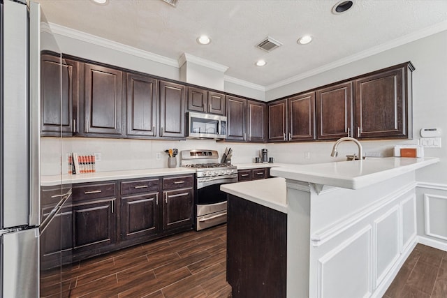 kitchen with appliances with stainless steel finishes, dark brown cabinetry, a kitchen bar, and kitchen peninsula