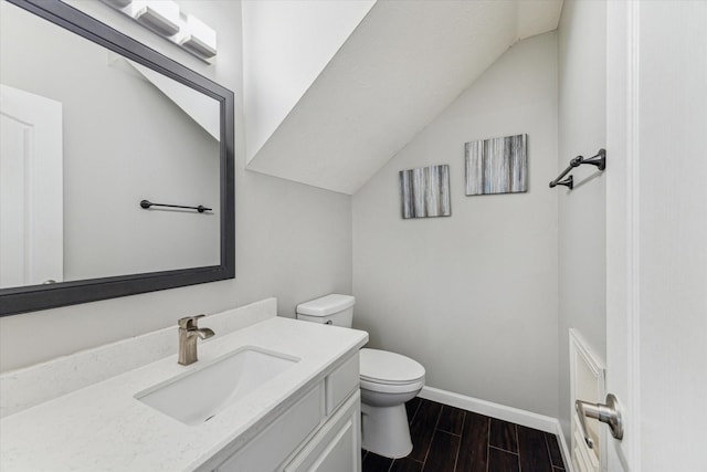 bathroom with toilet, lofted ceiling, and vanity