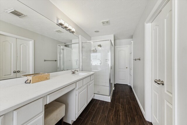 bathroom featuring vanity, a textured ceiling, and a shower with shower door