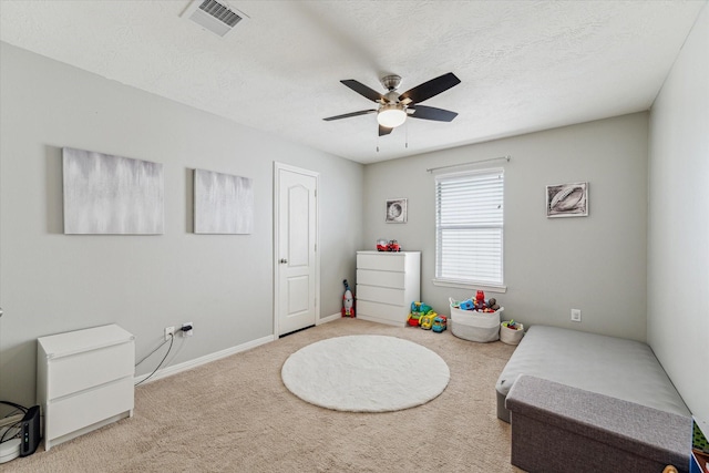 carpeted bedroom with ceiling fan and a textured ceiling