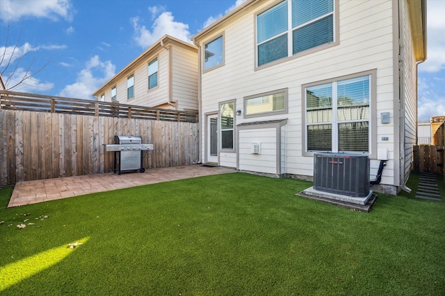 back of property with a patio, a yard, and central AC