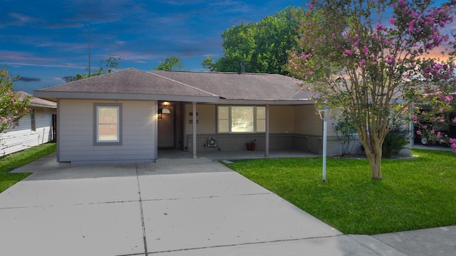 ranch-style home featuring a carport and a lawn