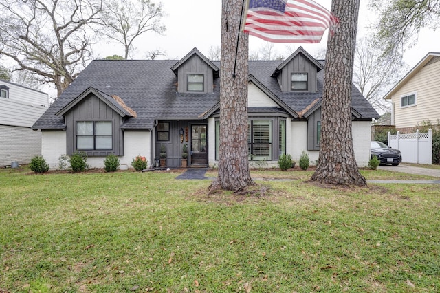 view of front facade with roof with shingles, a front lawn, and brick siding