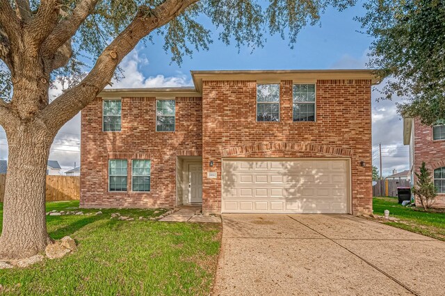 traditional-style home with driveway, an attached garage, a front yard, and brick siding