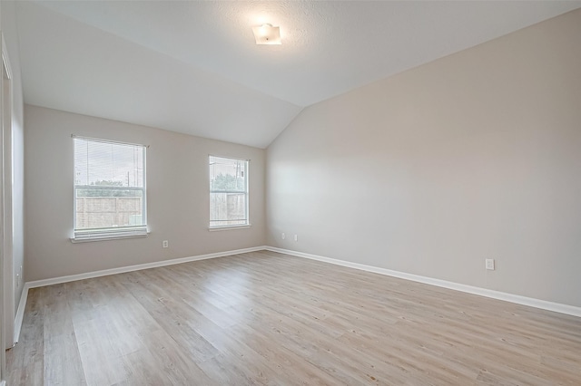 unfurnished room with light wood-style flooring, baseboards, and vaulted ceiling