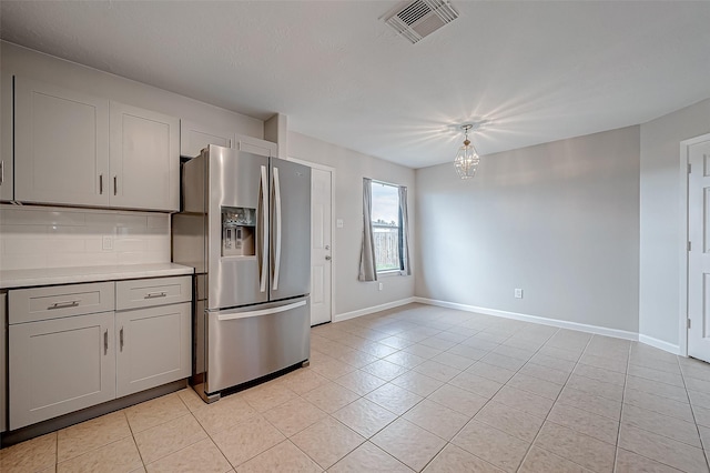 kitchen with visible vents, light countertops, stainless steel fridge with ice dispenser, tasteful backsplash, and pendant lighting