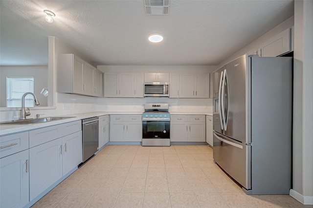 kitchen with a sink, visible vents, light countertops, appliances with stainless steel finishes, and decorative backsplash