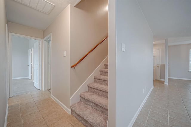 stairs with tile patterned flooring, visible vents, and baseboards