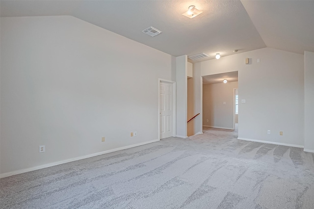 unfurnished room with visible vents, vaulted ceiling, light carpet, and baseboards