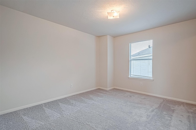 empty room with carpet flooring, a textured ceiling, and baseboards