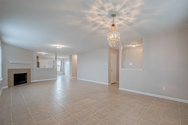 unfurnished living room with a notable chandelier, light tile patterned flooring, a tile fireplace, and baseboards