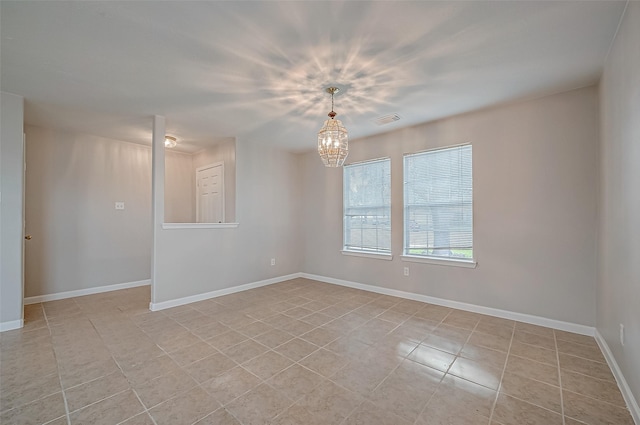 empty room with visible vents, a notable chandelier, and baseboards