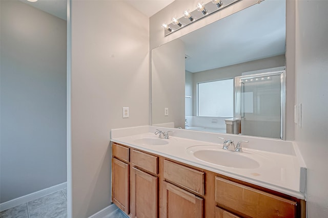 full bathroom with double vanity, a stall shower, baseboards, and a sink