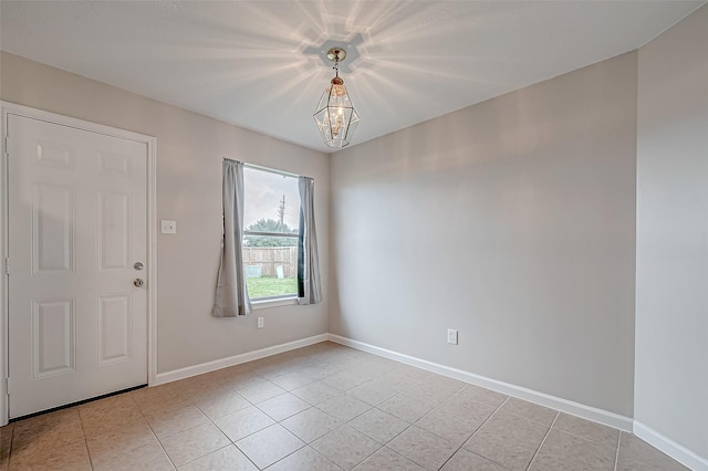 empty room featuring light tile patterned floors, baseboards, and a notable chandelier