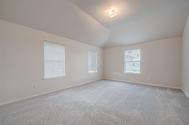 unfurnished room with lofted ceiling, baseboards, and light colored carpet