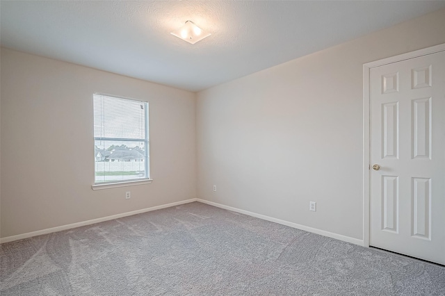 unfurnished room featuring light carpet and baseboards