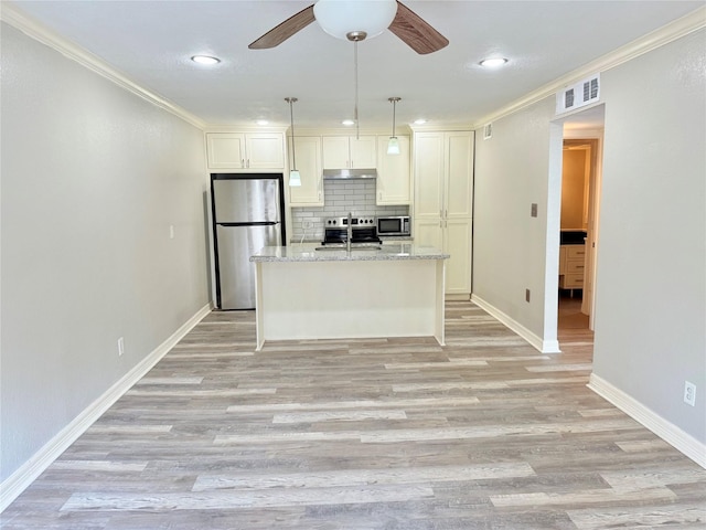 kitchen featuring tasteful backsplash, stainless steel appliances, light stone counters, white cabinetry, and a kitchen island with sink