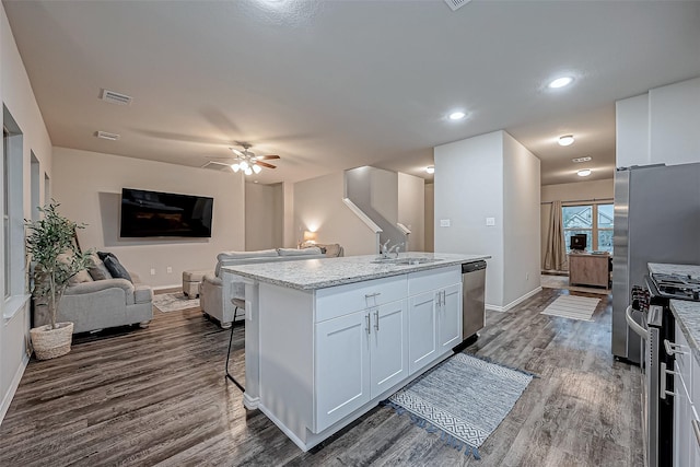 kitchen featuring a center island with sink, appliances with stainless steel finishes, sink, light stone counters, and white cabinets