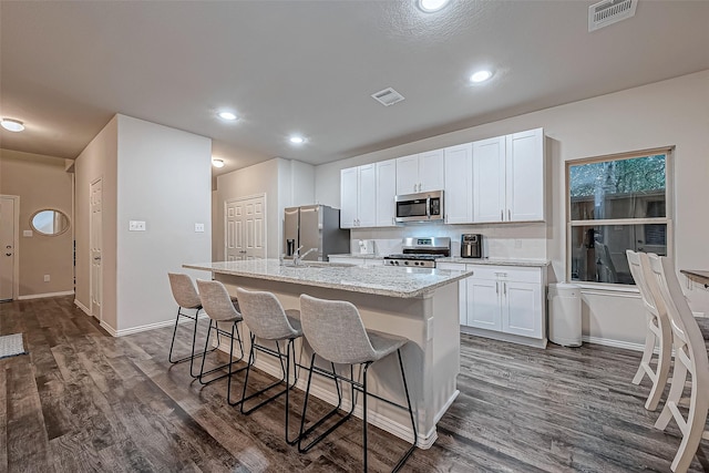 kitchen with a center island with sink, dark wood-type flooring, stainless steel appliances, and white cabinetry