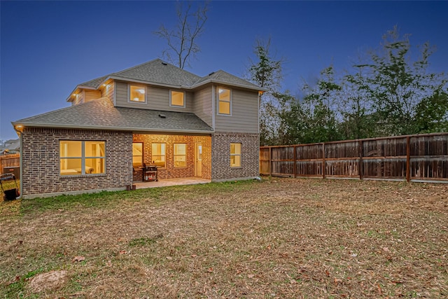 rear view of house with a patio and a lawn