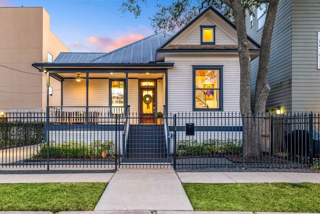 view of front of house featuring covered porch, a fenced front yard, a gate, and metal roof