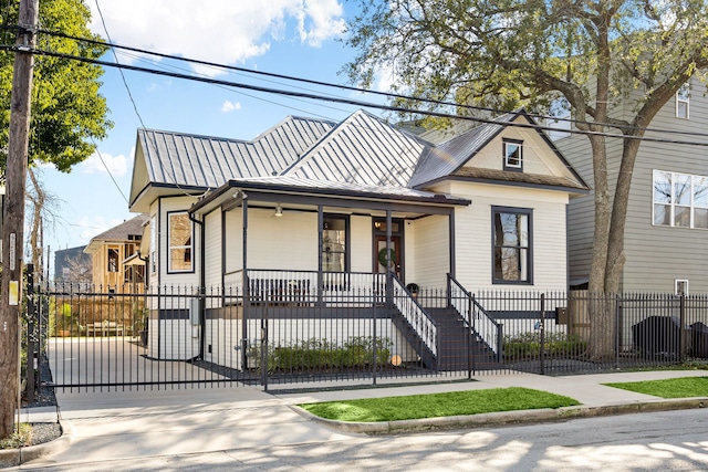 view of front facade featuring covered porch, a fenced front yard, a gate, and metal roof