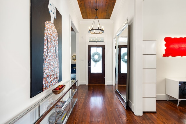 foyer entrance with dark wood-style floors, baseboards, ornamental molding, and a notable chandelier