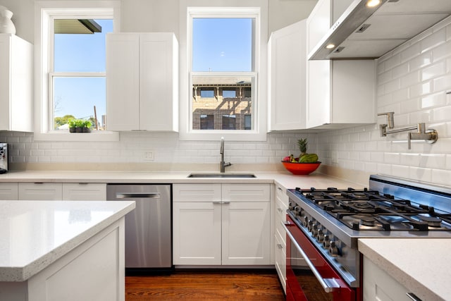 kitchen featuring appliances with stainless steel finishes, a wealth of natural light, white cabinets, and a sink