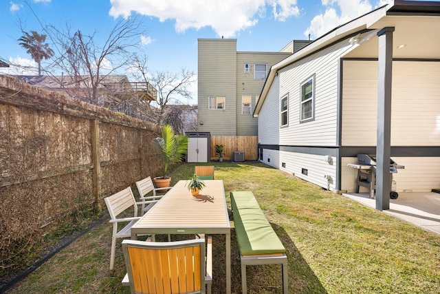 view of yard featuring a storage shed, outdoor dining area, an outdoor structure, and a fenced backyard