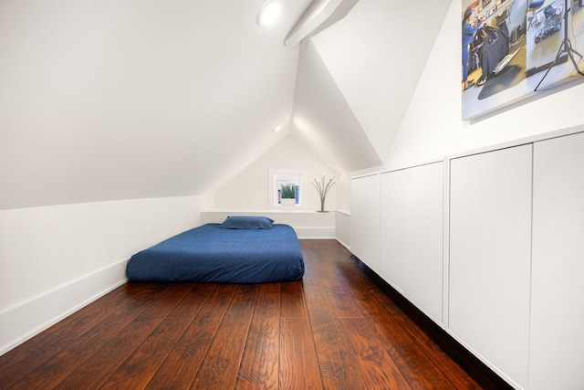 bedroom featuring dark wood-style floors, vaulted ceiling, and two closets